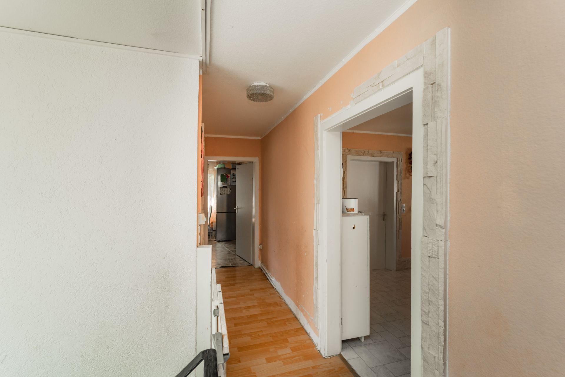Ein Flur mit Holzfußboden und mehreren Türen zu angrenzenden Räumen in einer Wohnung.