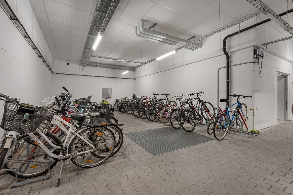 Fahrradraum mit mehreren abgestellten Fahrrädern auf betoniertem Boden.