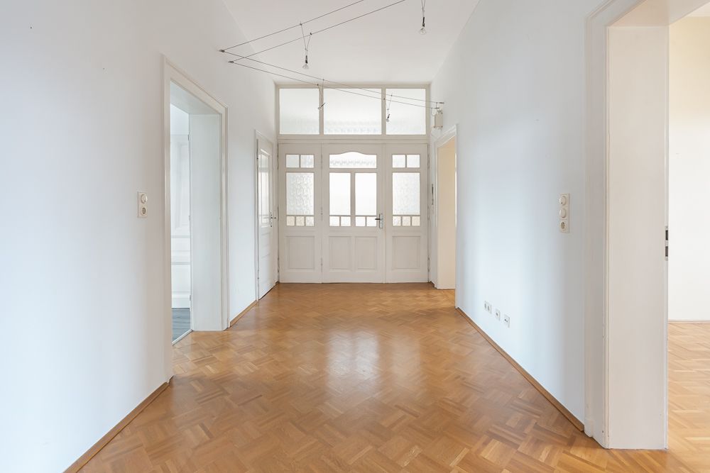 Heller Flur mit Holzboden, weißen Wänden und mehreren offenen Türen.