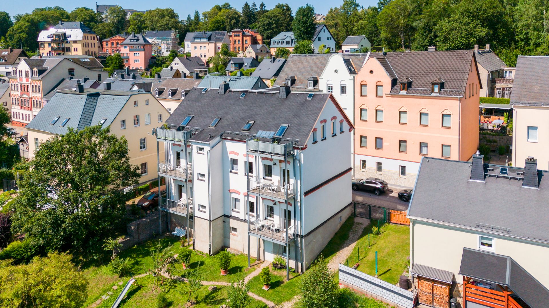 Mehrfamilienhaus mit Balkonen, umgeben von weiteren Wohnhäusern und viel Grün.