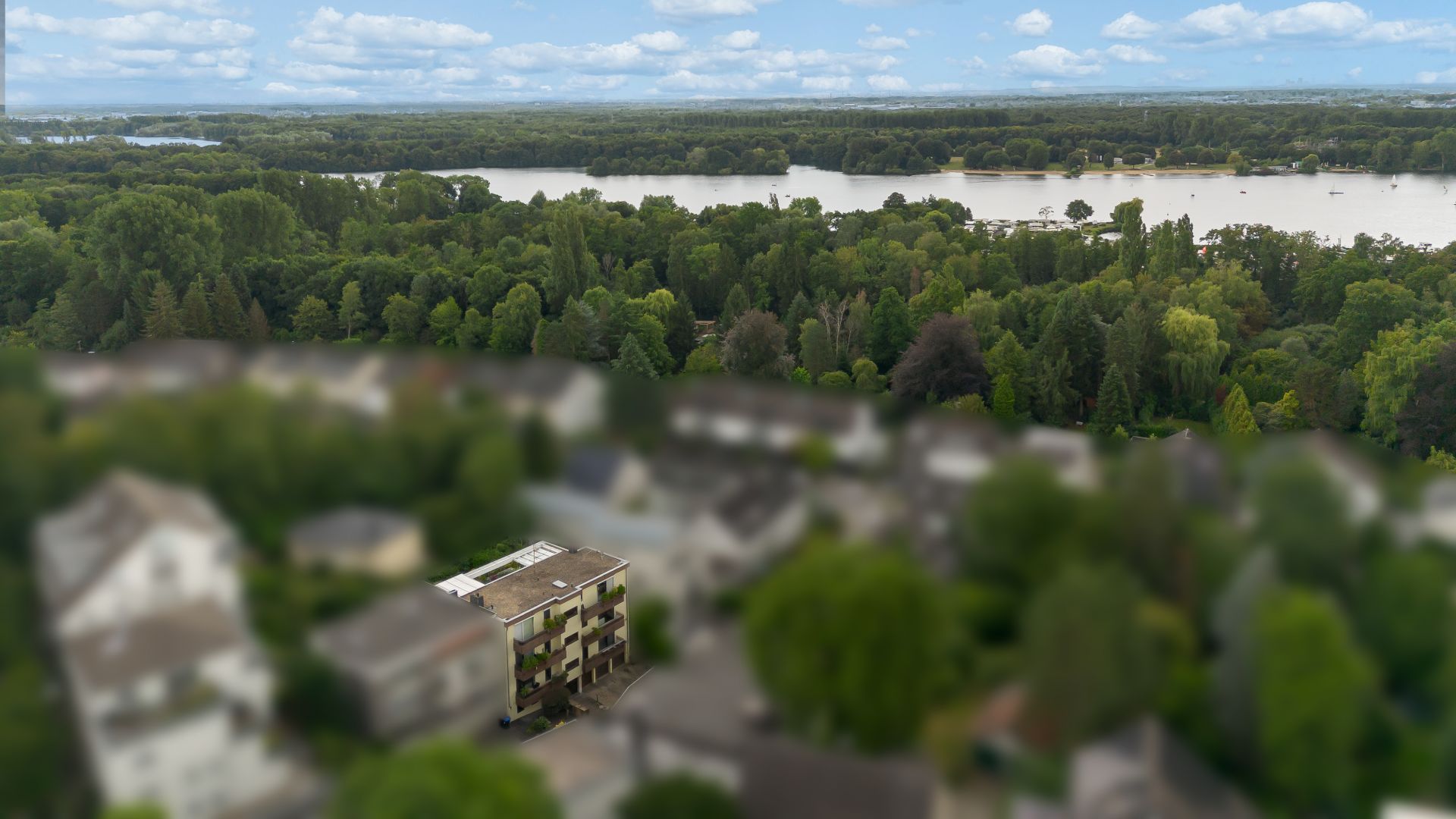 Wohnhaus im Vordergrund mit Blick auf einen Fluss und viele Bäume im Hintergrund.