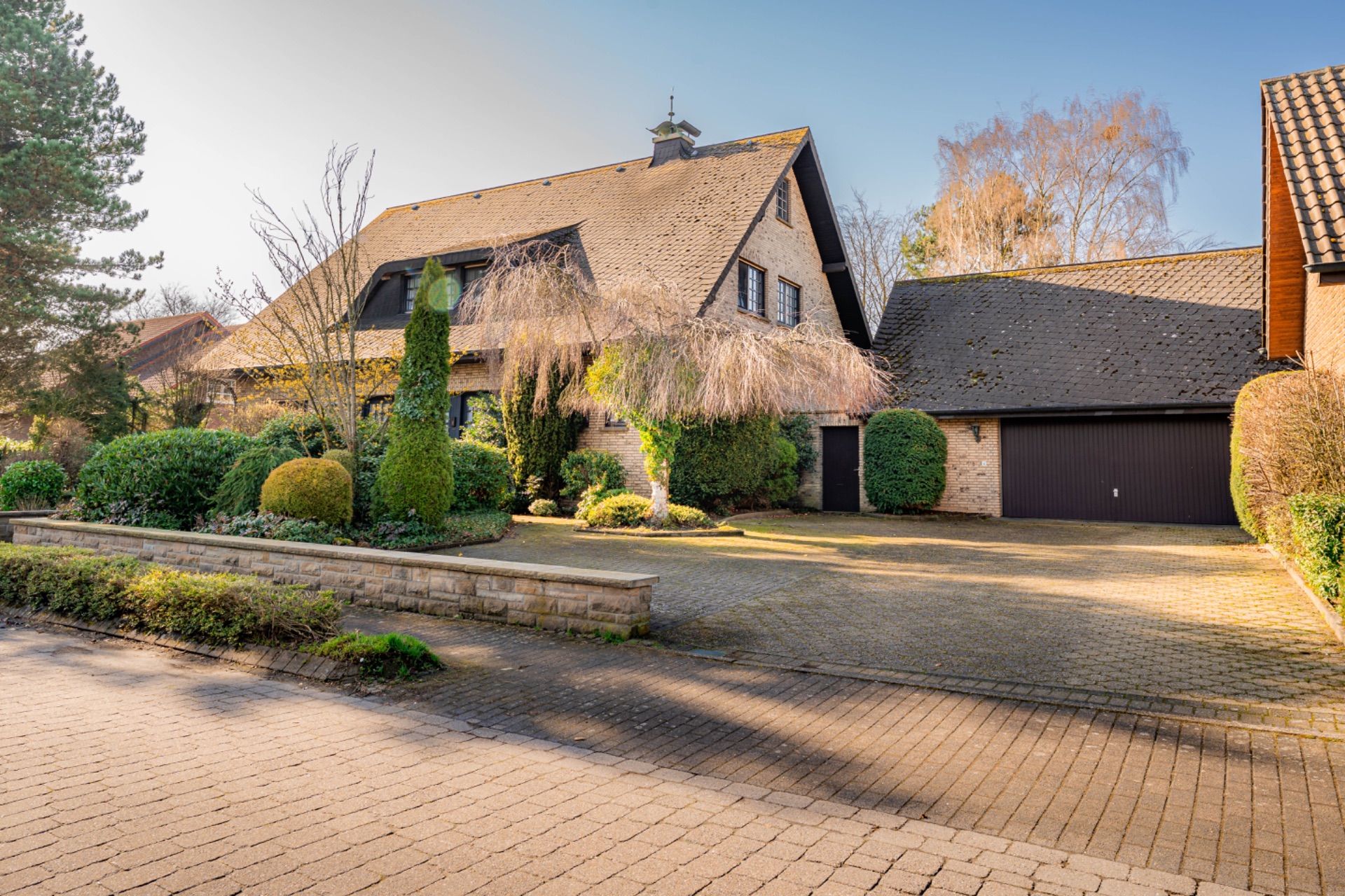 Großes Einfamilienhaus mit schrägem Dach, Garage und gepflegtem Vorgarten.