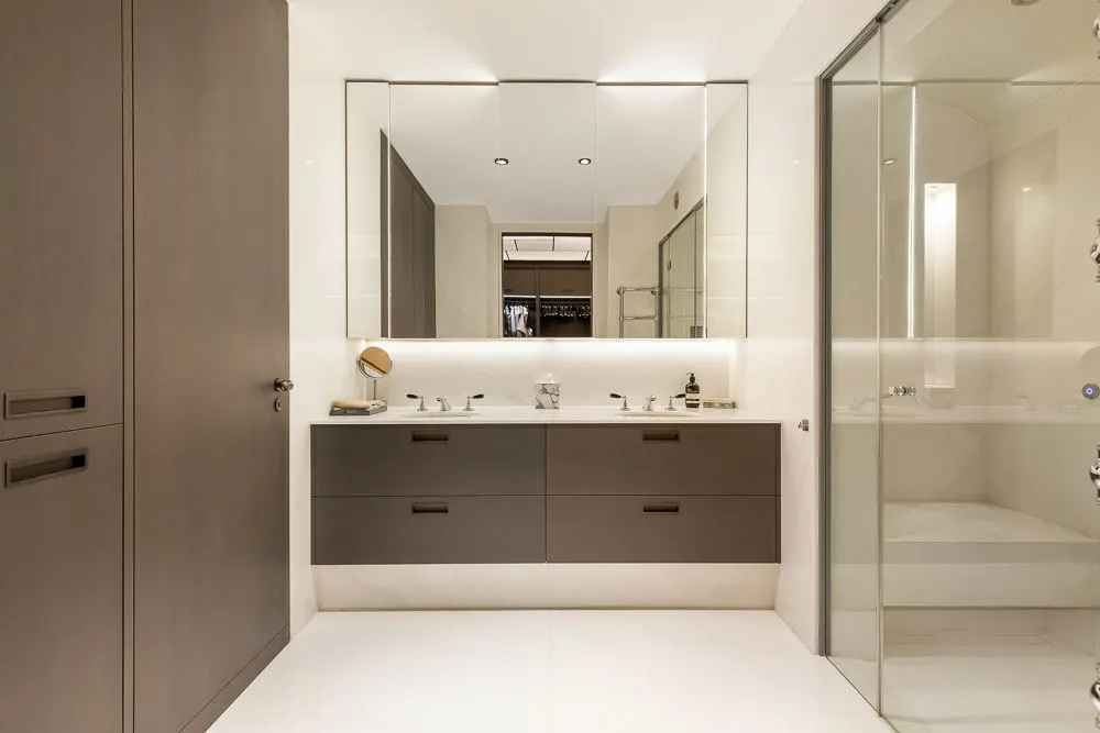 Modernes Badezimmer mit Doppelwaschbecken, großem Spiegel und Glastür zur Dusche.
