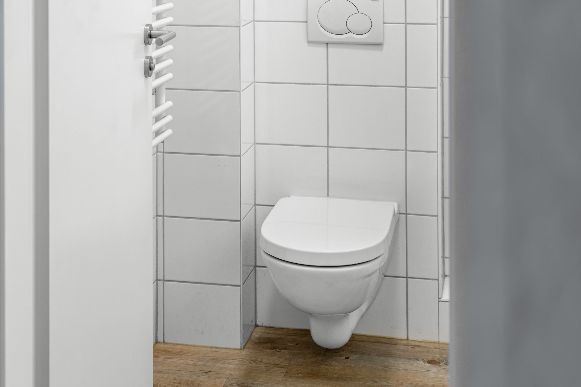 Moderne Toilette mit weißem Fliesenspiegel und Holzboden in einem Badezimmer.