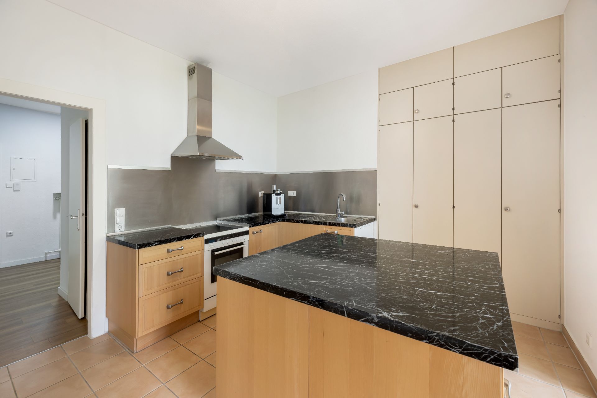 Moderne Küche mit schwarzen Arbeitsplatten, Holzschränken und großem Einbauschrank.