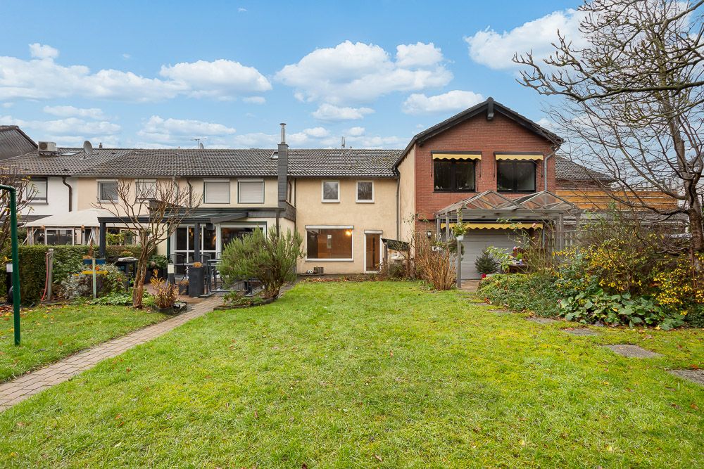 Blick auf Reihenhaus mit Garten und überdachter Terrasse im Hinterhof.