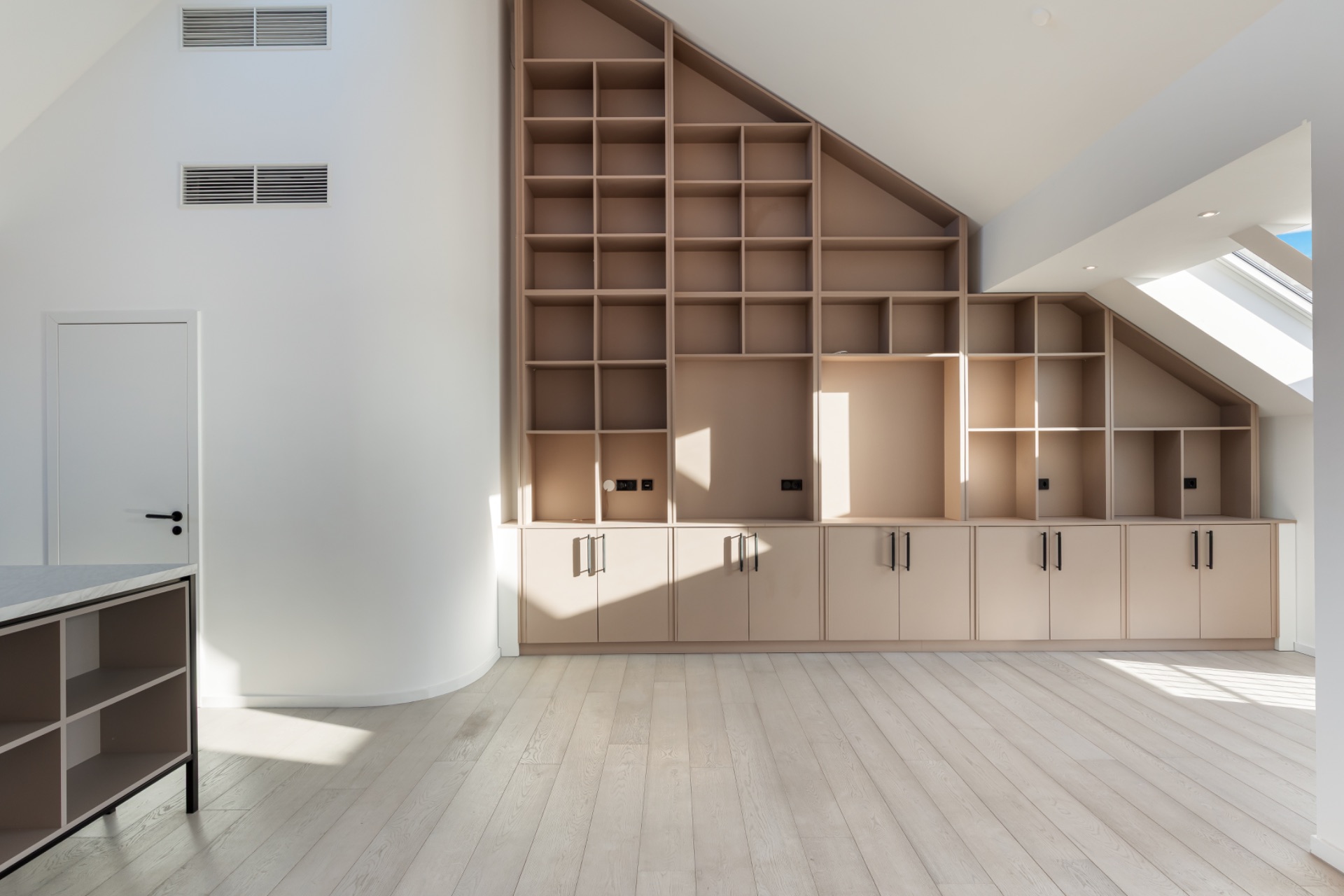 Helles Zimmer mit schräger Decke, großem offenen Regal und Einbauschränken.