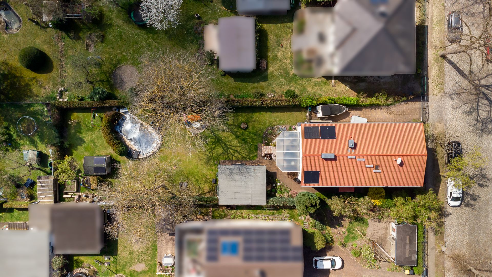 Luftaufnahme eines Hauses mit rotem Dach, Garten und umgebenden Gebäuden.