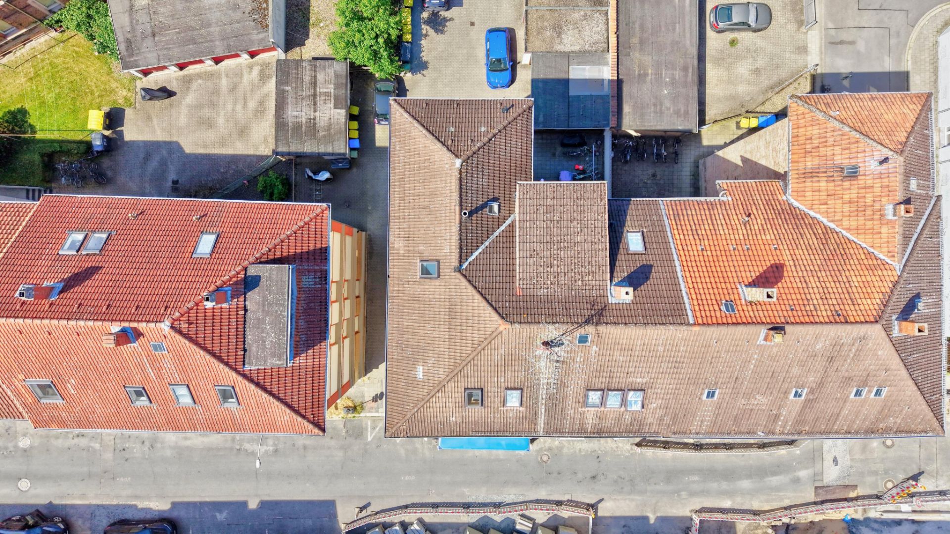 Luftaufnahme von Wohnhäusern mit roten und braunen Dächern an einer Straße.