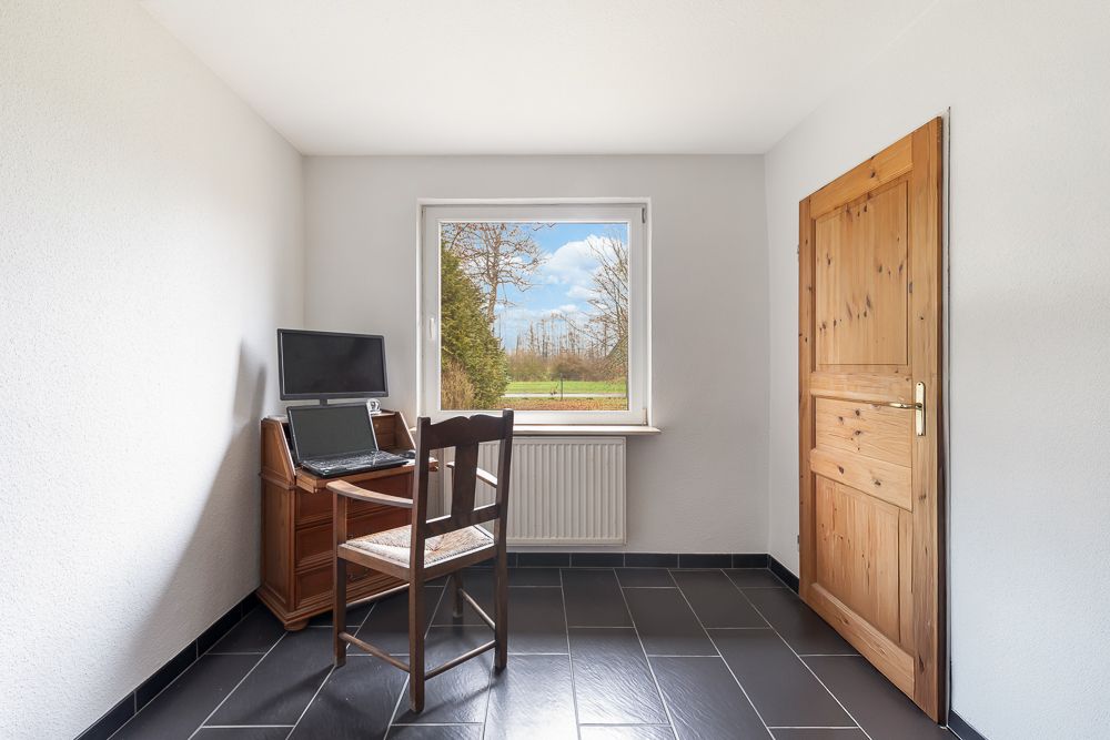 Kleines Arbeitszimmer mit Schreibtisch, Stuhl, Computer und Fenster mit Ausblick.