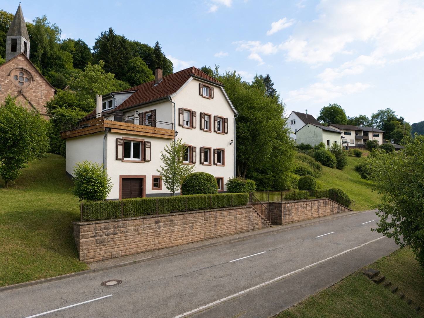 Zweistöckiges Wohnhaus mit rotem Dach an einer ruhigen Straße, umgeben von Bäumen und Hecken.