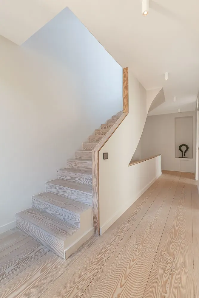 Heller Flur mit Holztreppe und Holzfußboden in einem Wohnhaus.