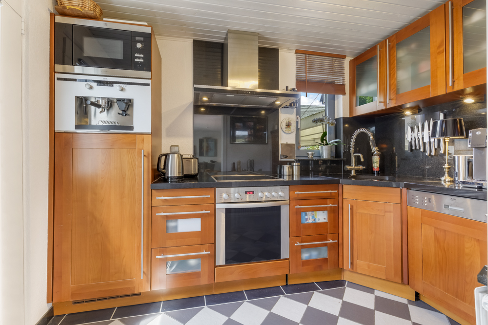 Moderne Küche mit Holzmöbeln, Geräten, Spüle und Messern an der Wand.