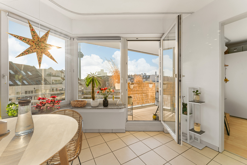 Heller Wohnraum mit Esstisch, Pflanzen, Stern-Deko und Zugang zum Balkon.