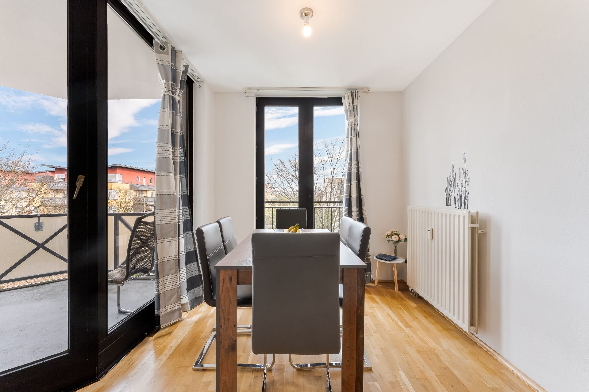 Essbereich mit Holztisch, vier Stühlen und großen Fenstern zu einem Balkon.