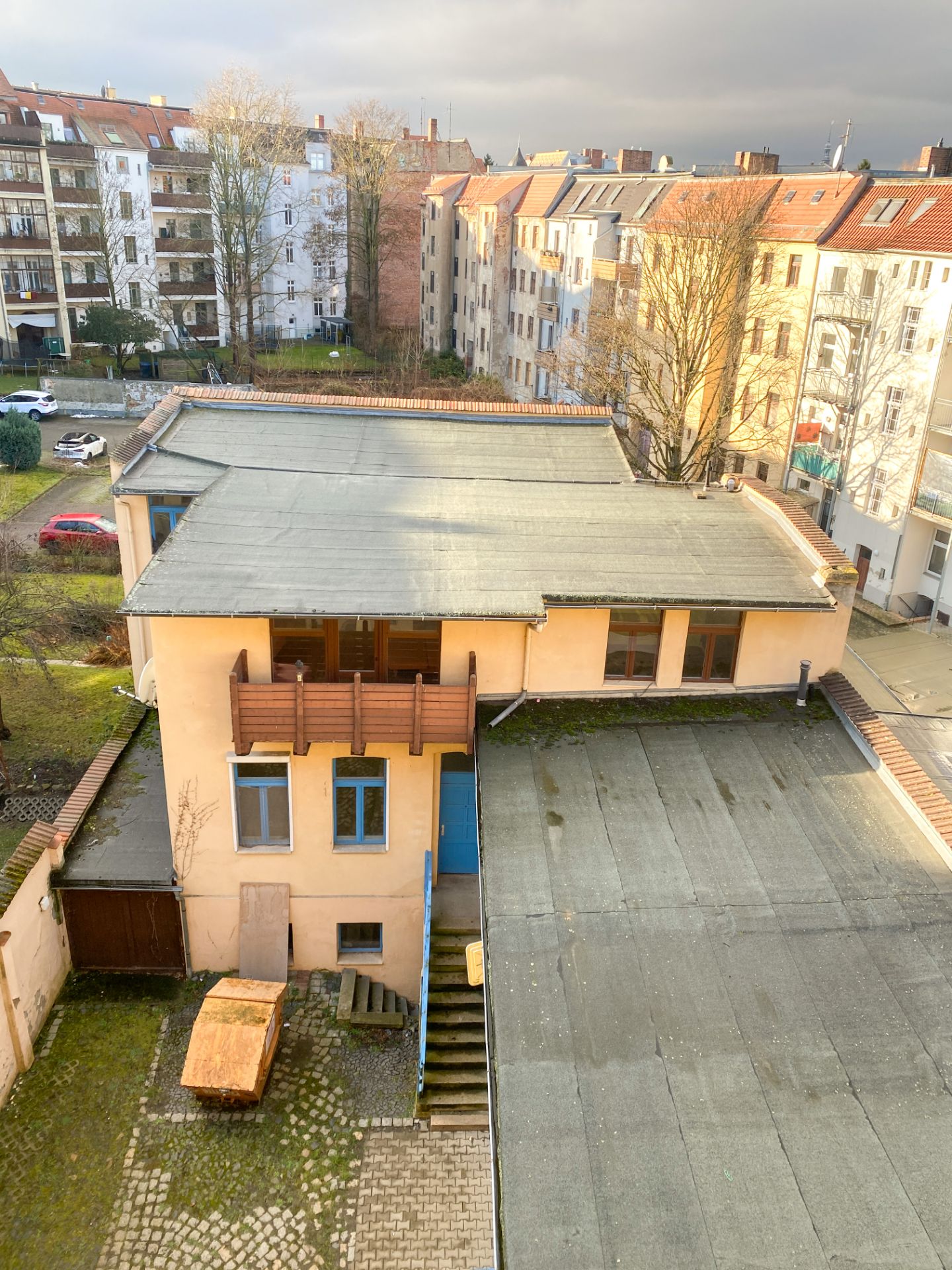 Blick auf einen Innenhof mit flachem Nebengebäude, umgeben von mehrstöckigen Wohnhäusern.