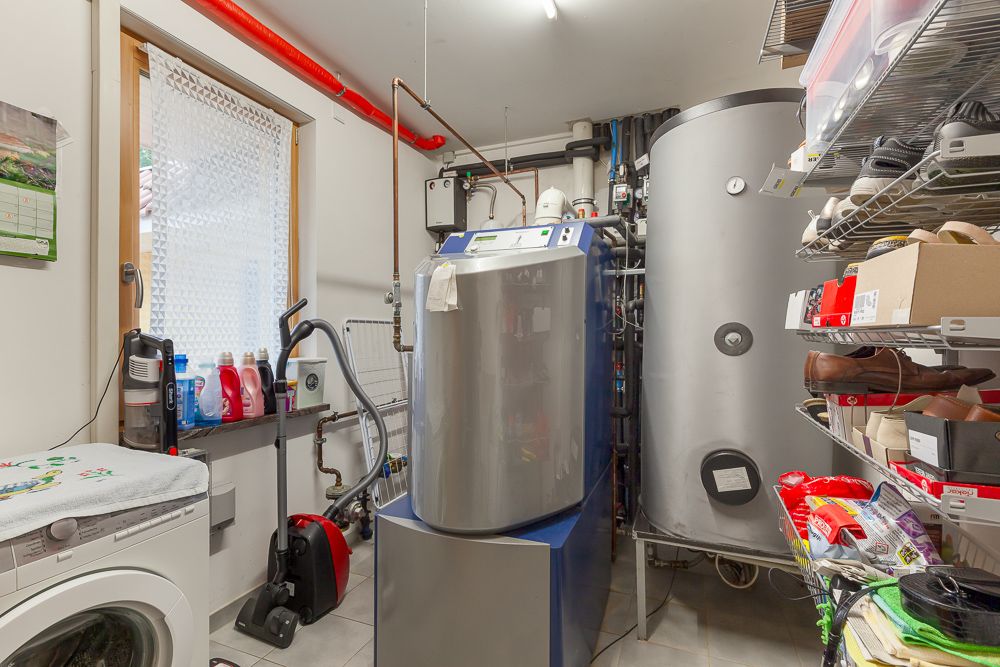 Hauswirtschaftsraum mit Waschmaschine, Regalen, Heizungsanlage und Haushaltsgegenständen.