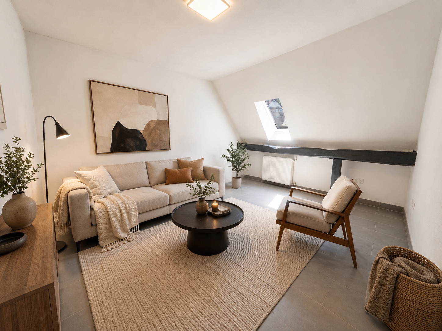 Helles Wohnzimmer mit Sofa, Sessel, Teppich, Couchtisch und Dachfenster.