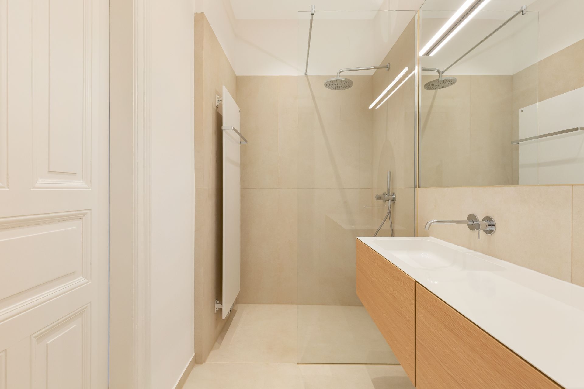 Modernes Badezimmer mit begehbarer Dusche, Holzwaschtisch und großem Spiegel.