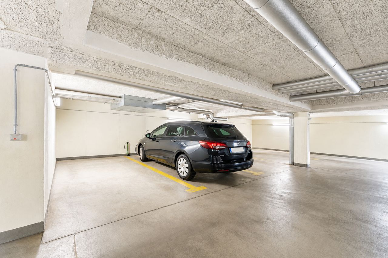 Schwarzer Kombi parkt in heller Tiefgarage mit markierter Parkfläche.