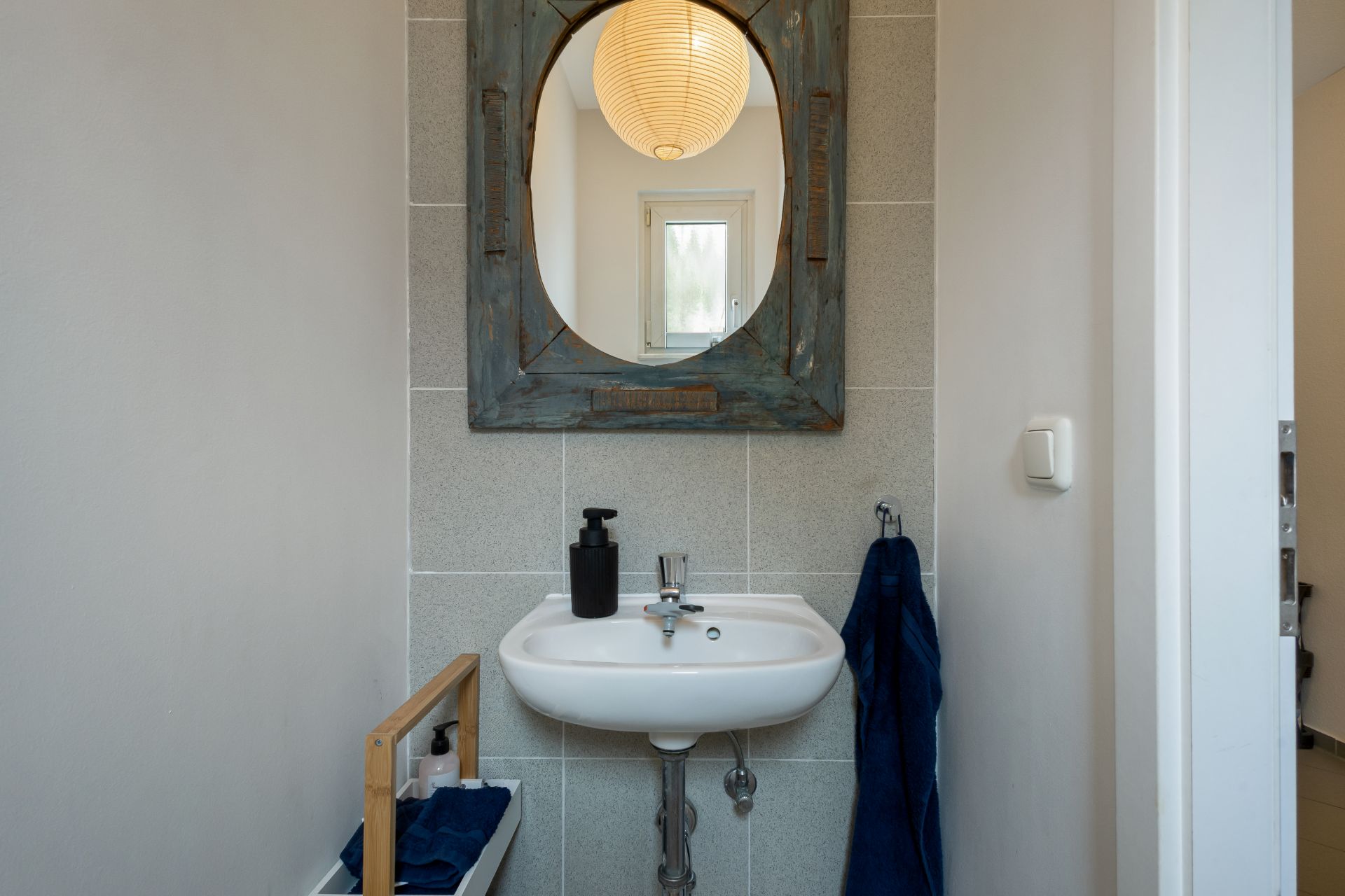 Kleines Bad mit Waschbecken, Spiegel und Handtuch an der Wand.