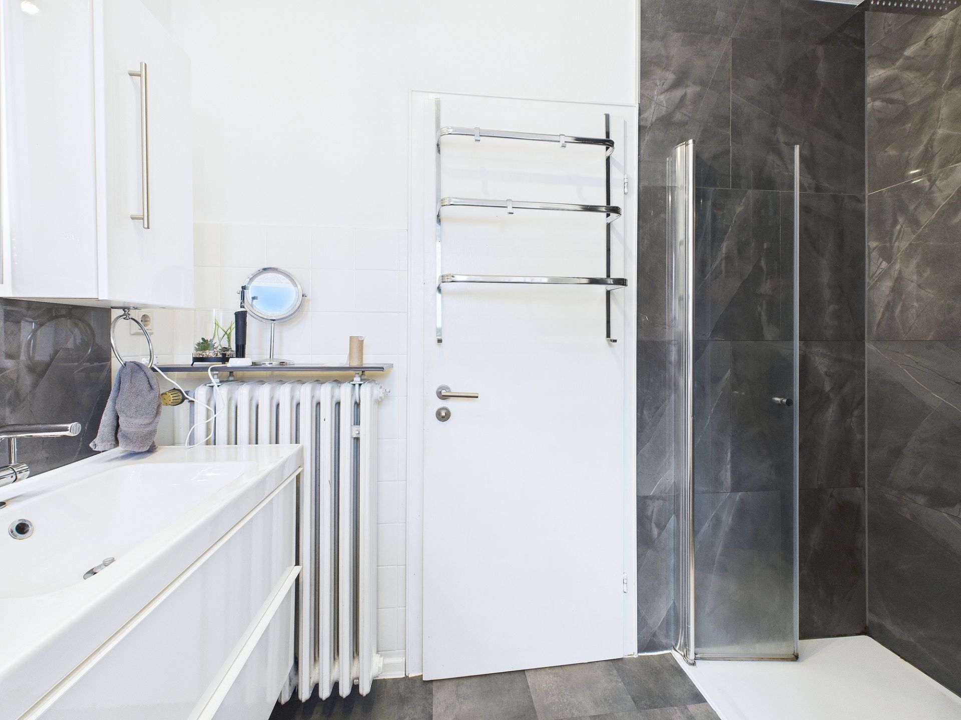 Modernes Badezimmer mit Waschbecken, Duschkabine und Handtuchhalter an der Tür.