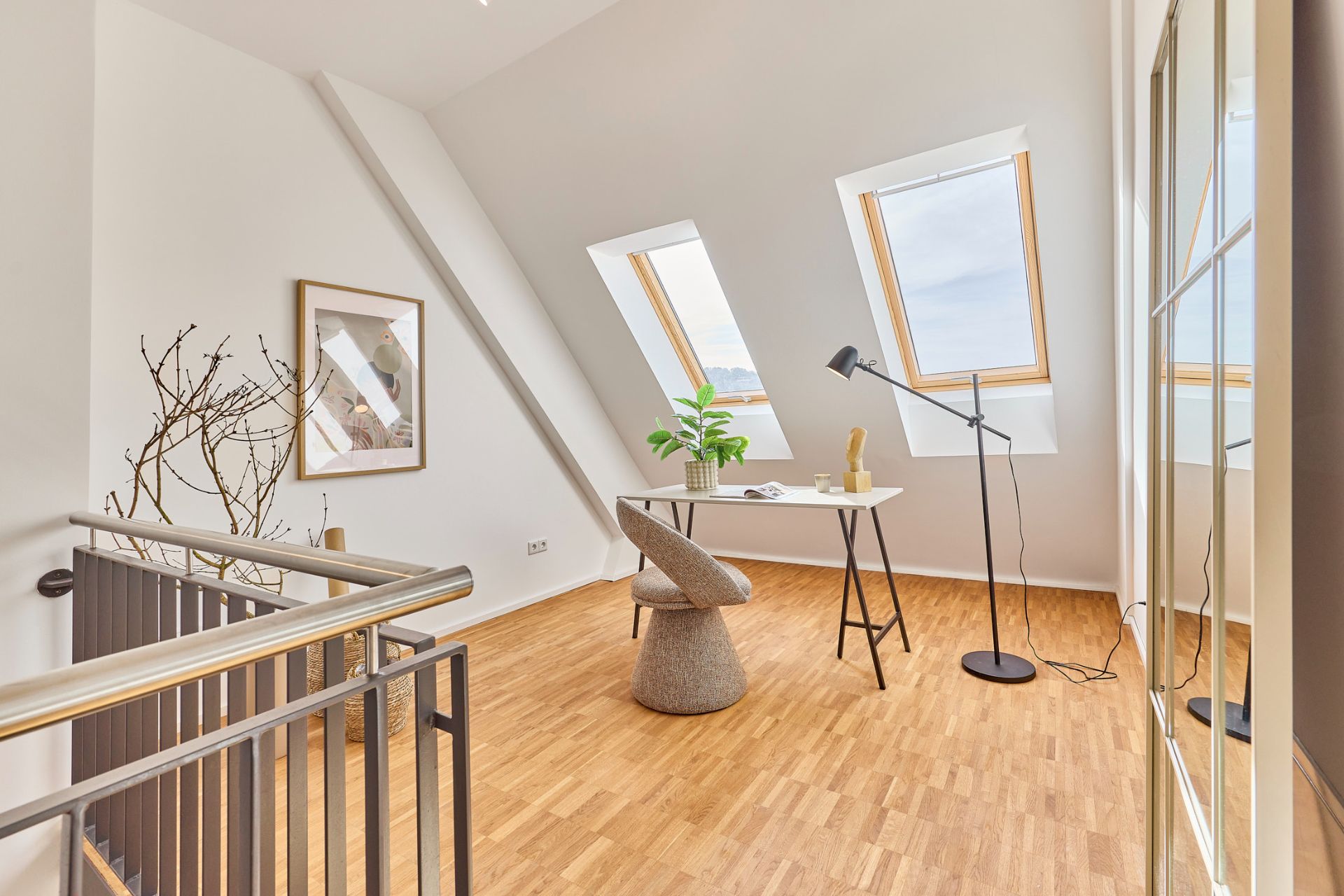 Helles Arbeitszimmer mit Schreibtisch, Stuhl, Stehlampe und zwei Dachfenstern auf Holzfußboden.