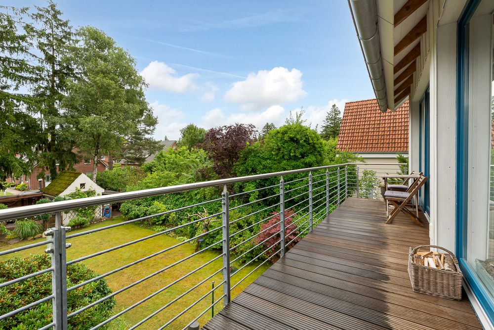 Holzbalkon mit Metallgeländer, Blick auf Garten mit Bäumen und Rasen.