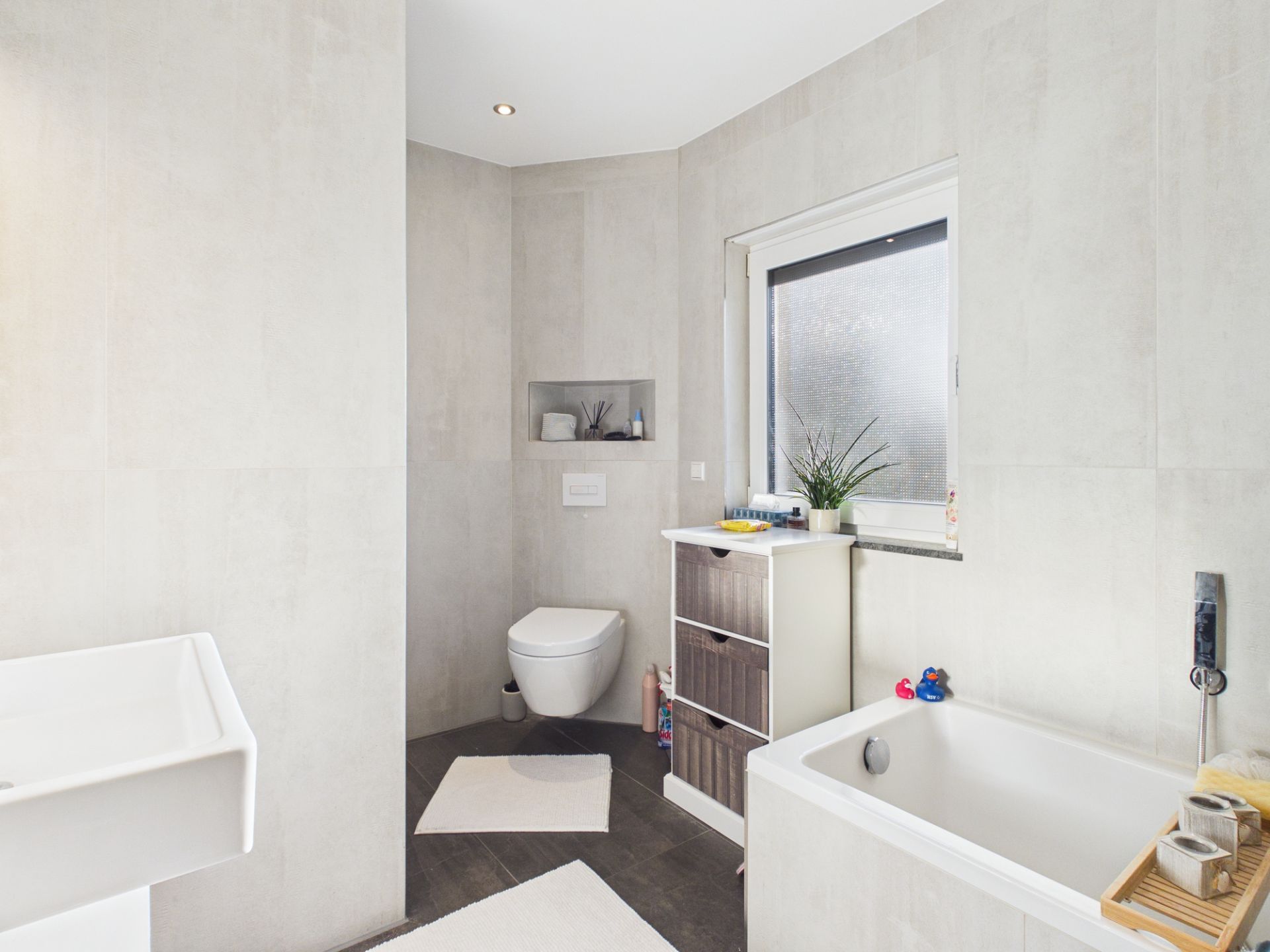 Modernes Badezimmer mit Badewanne, Waschbecken, Toilette und Fenster.