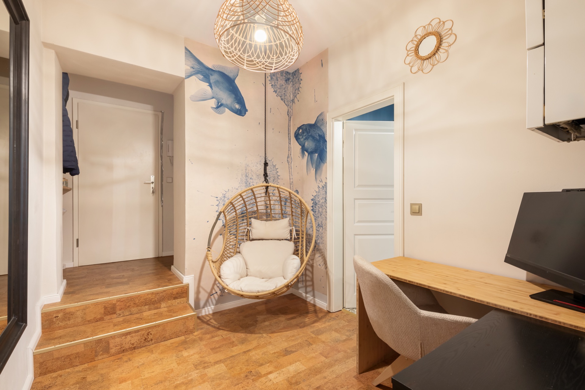 Heller Flur mit Schreibtisch, Hängesessel, Wand mit Fischen und Holzfußboden.