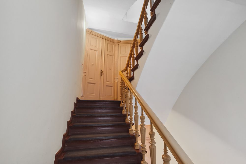 Treppe mit Holzgeländer führt zu einer beigen Tür im Innenbereich.