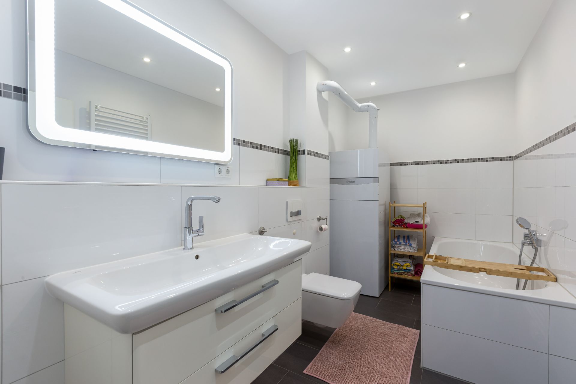 Modernes Badezimmer mit großem Spiegel, Waschbecken, Toilette und Badewanne.