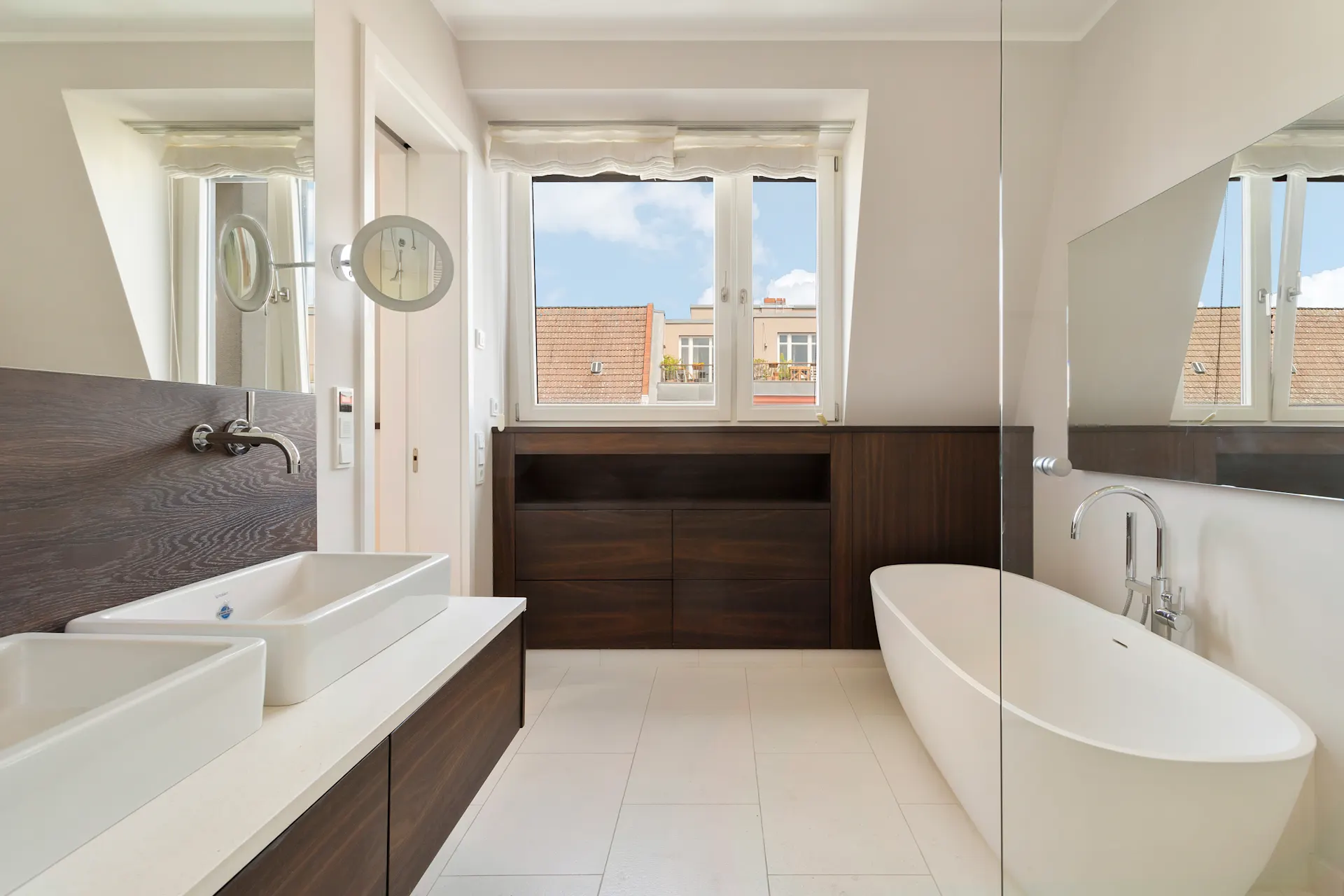 Modernes Badezimmer mit freistehender Badewanne und zwei Waschbecken unter Fenstern.