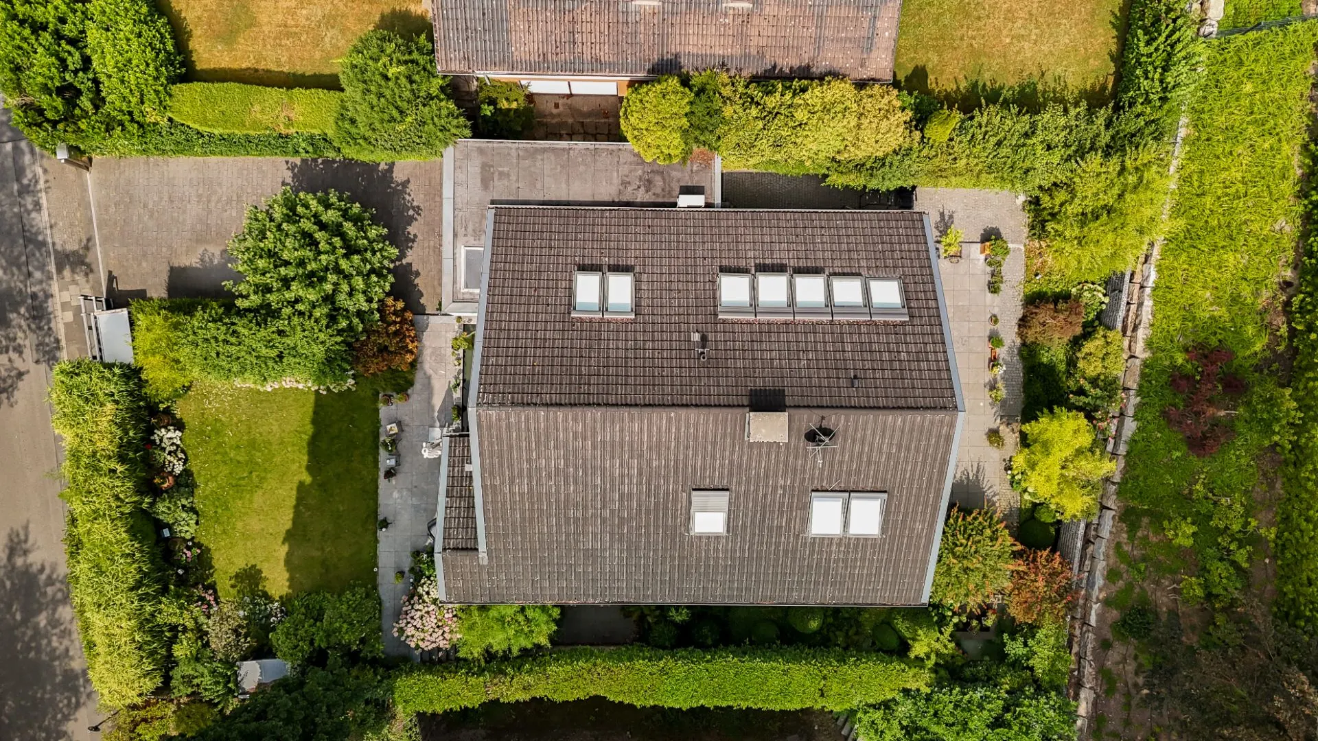 Luftaufnahme eines Einfamilienhauses mit Garten und umgebender Begrünung.