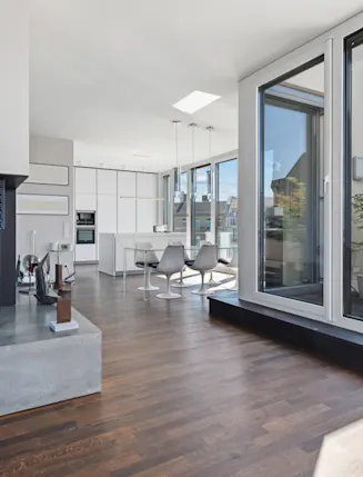 Modernes Wohnzimmer mit Kamin, offener Küche und Zugang zu einer Terrasse mit Esstisch.