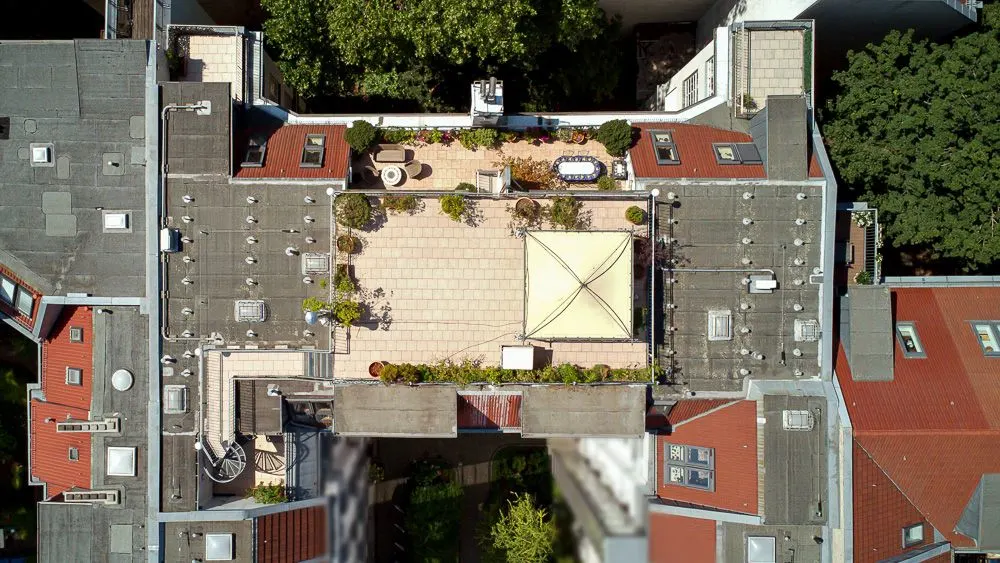 Luftaufnahme eines Innenhofs mit Terrasse, Pflanzen und Sitzbereich auf einem Wohngebäude.