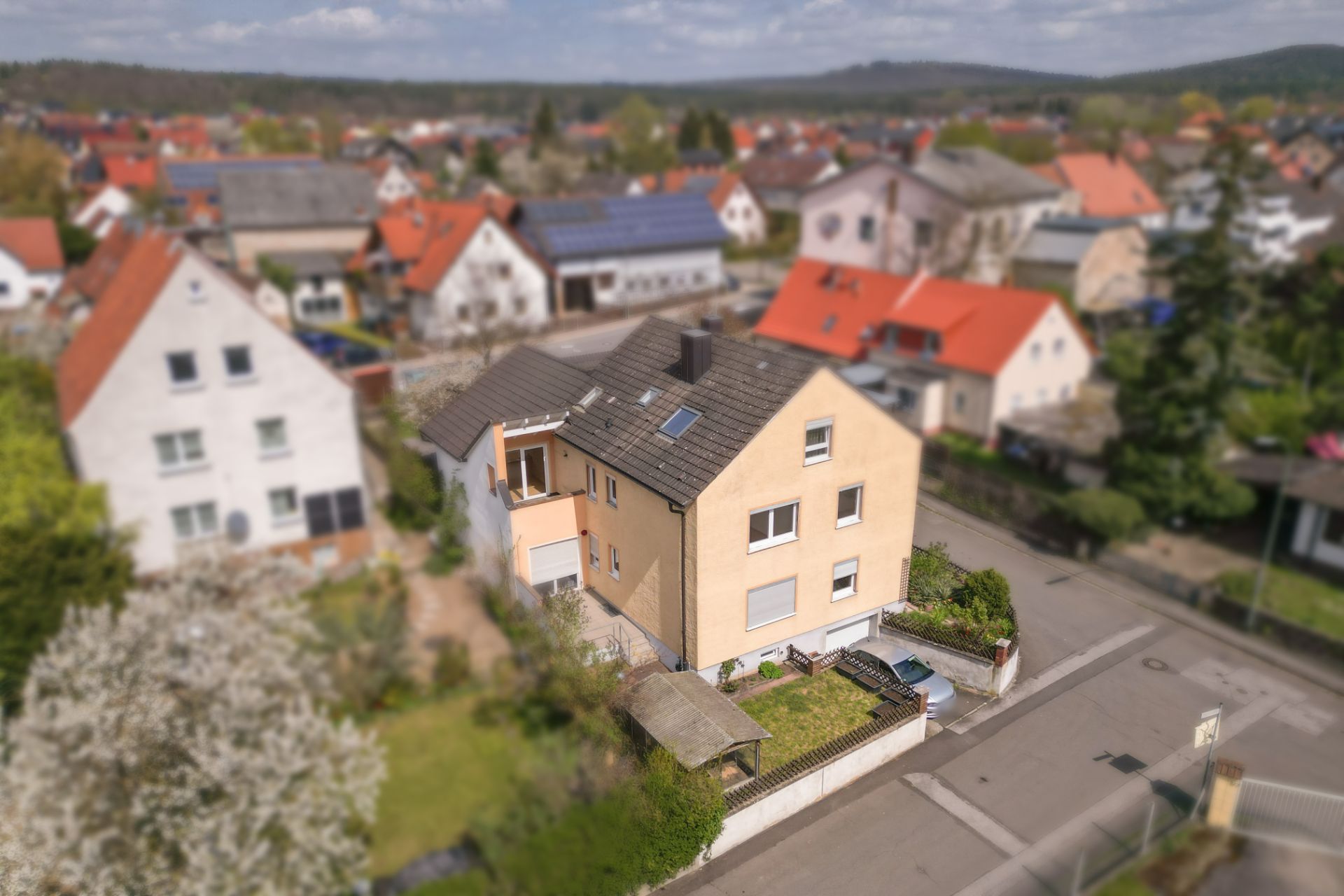 Freistehendes, zweistöckiges Haus mit Garten an einer Straßenecke in einem Wohngebiet.