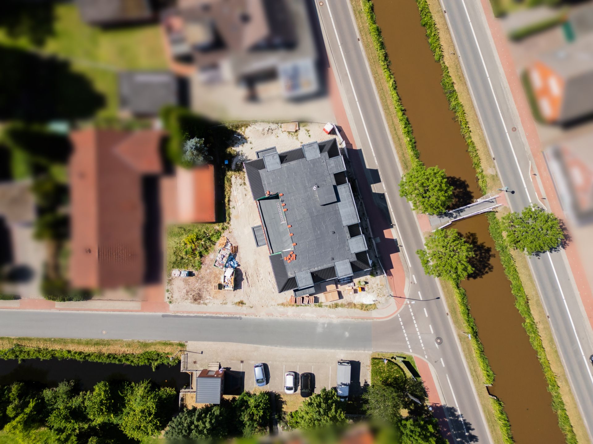 Luftaufnahme eines Wohngebäudes an einer Straße mit angrenzendem Kanal.