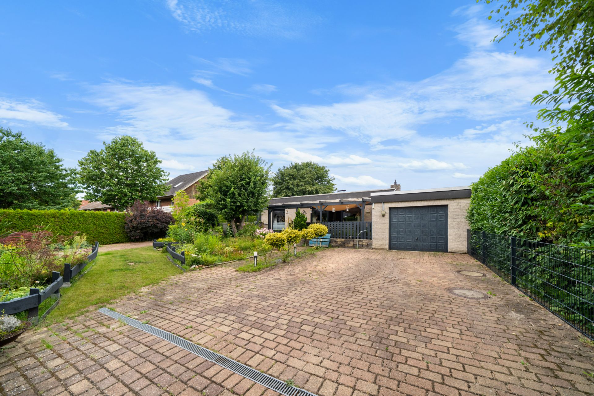 Einfamilienhaus mit gepflasterter Einfahrt, Garage und gepflegtem Garten.