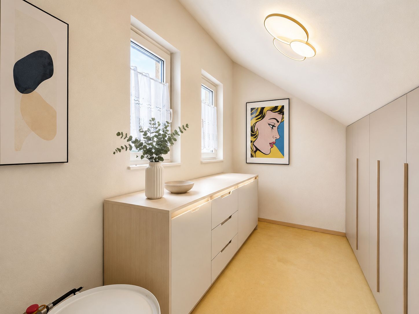 Heller Flur mit Kommode, Pflanzenvase, Schränken und Bildern an der Wand.