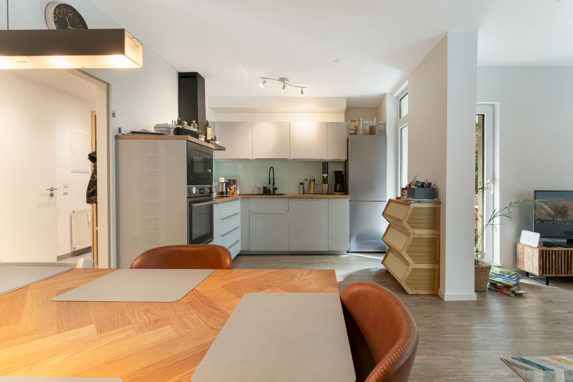 Moderne Wohnküche mit Esstisch, Holzregalen und Blick ins Wohnzimmer.