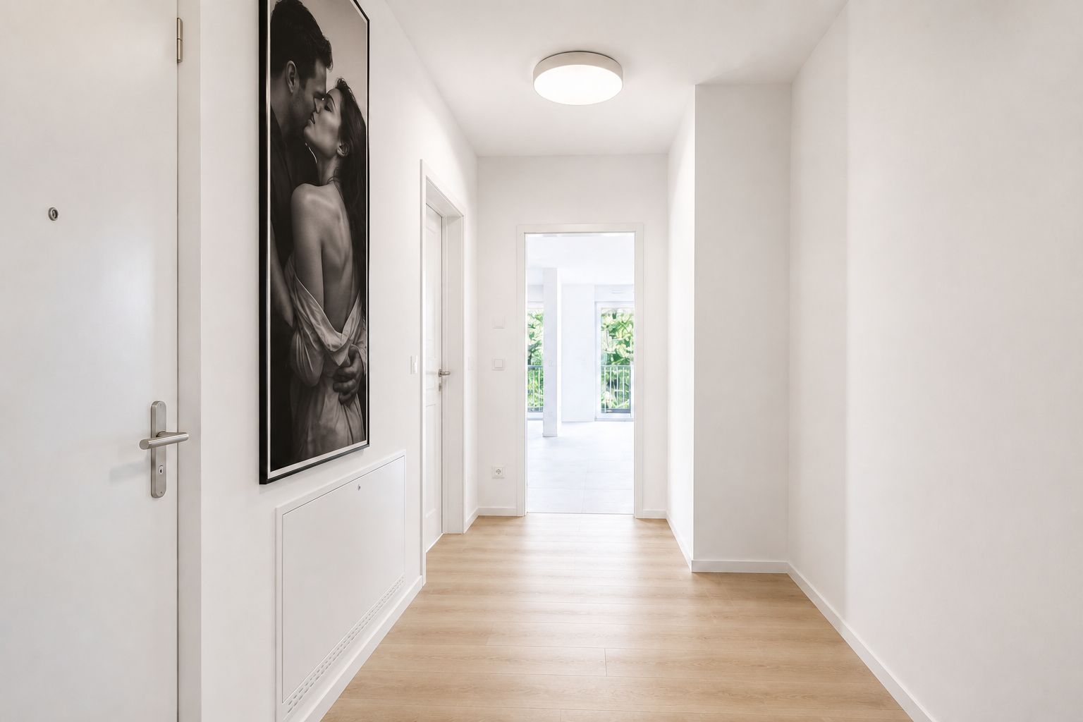 Heller Flur mit Holzfußboden, weißer Wand, Tür und großem Schwarzweißfoto an der Wand.