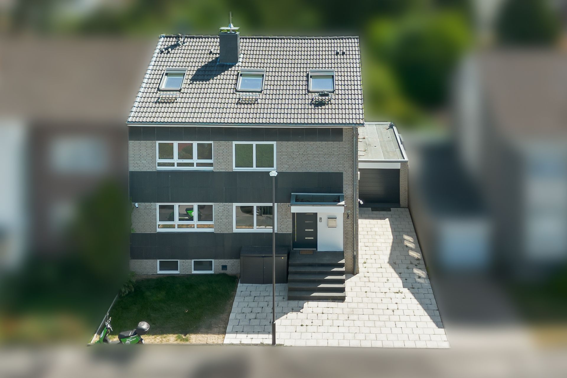 Modernes zweistöckiges Wohnhaus mit Flachdach, Garagenzufahrt und Vorgarten.