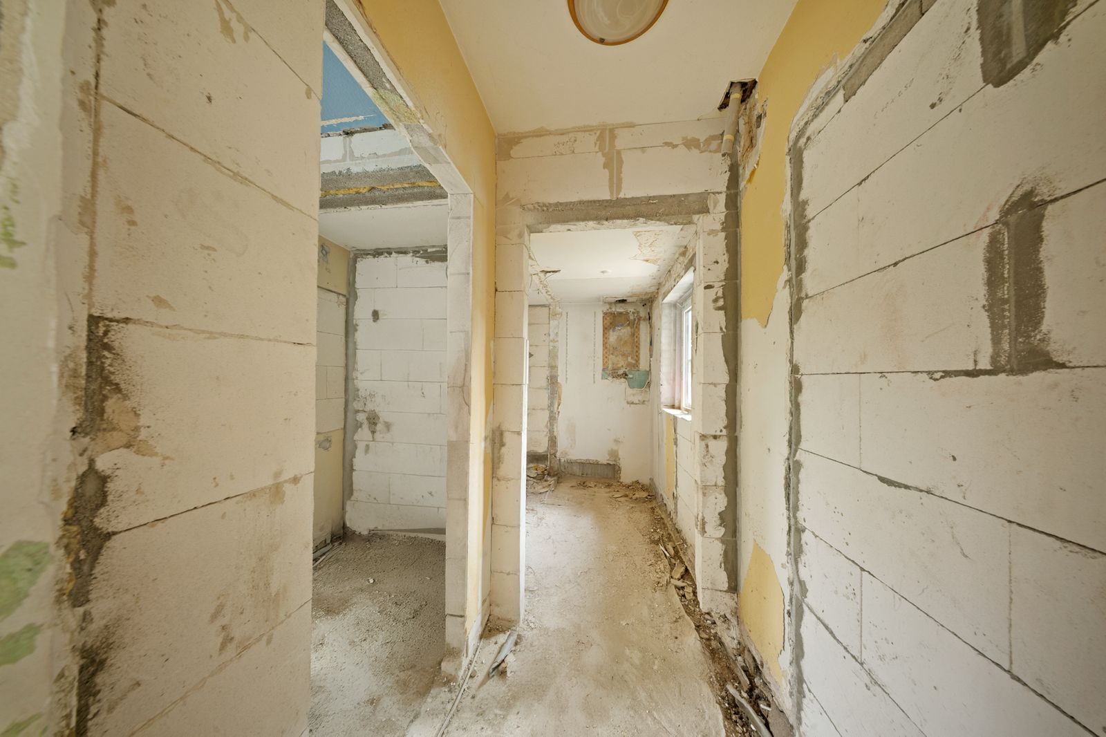 Flur in einem Haus im Rohbau mit sichtbaren unverputzten Wänden.