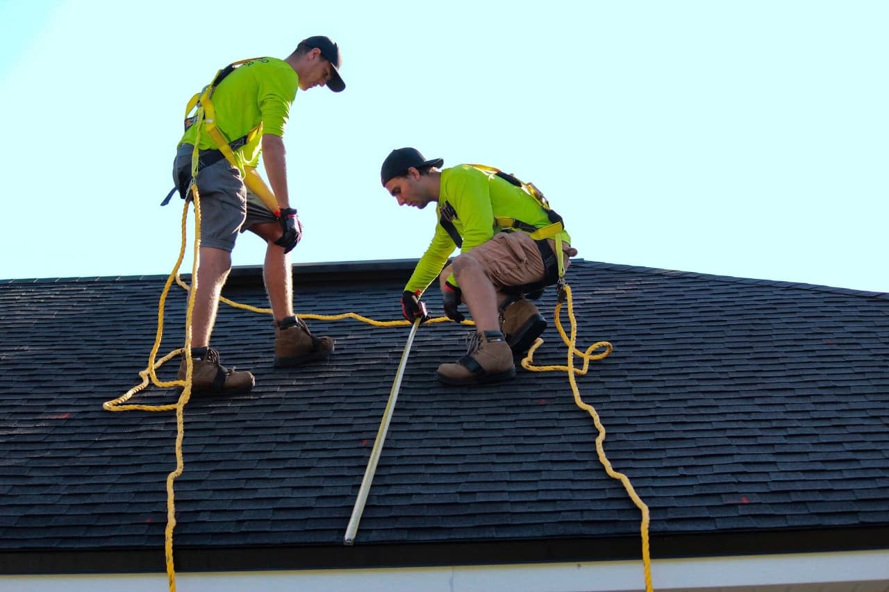 Two men from Taj Roofing Company doing maintenance to a shingle roof in Florida