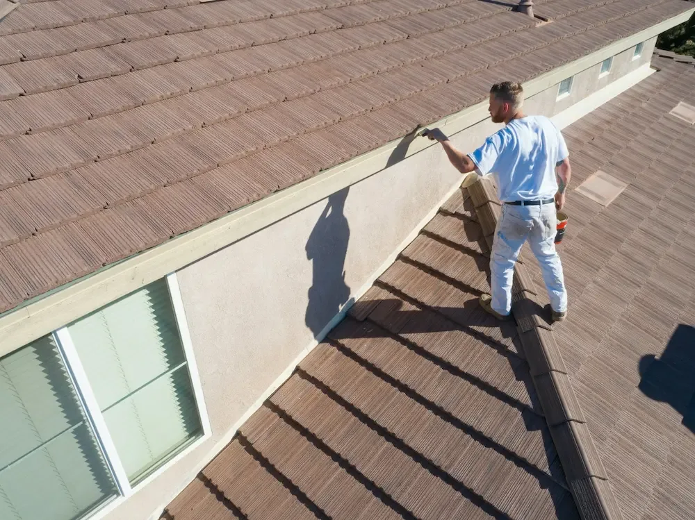 A worker from Taj Roofing checks a brown roof to see how much it would cost to replacing it