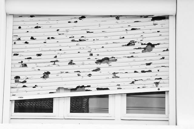 A white window damaged by a hailstorm