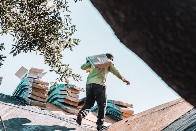 A man in green from Tajroofing company working on a roof