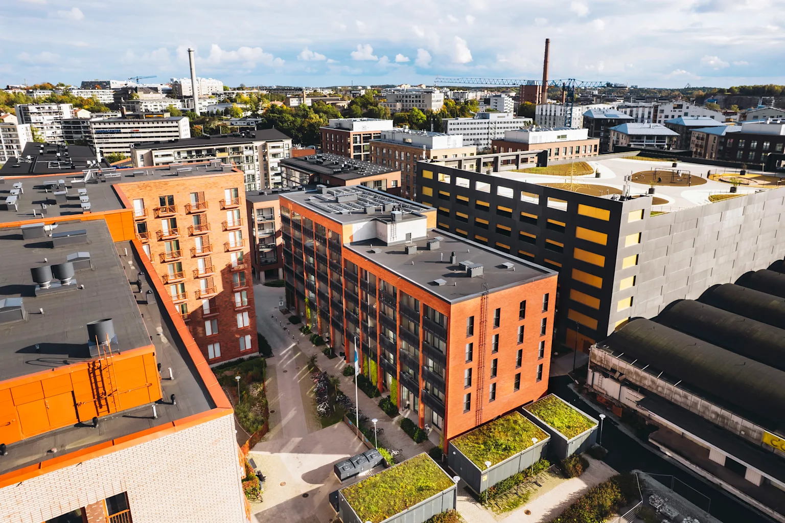 Ilmakuva Turun Herttuankulman asuinalueesta. Kuvassa näkyy industrial-henkisiä kerrostaloja, viheristutuksia sekä parkkihalli, jonka katolle on rakennettu leikkipuisto.
