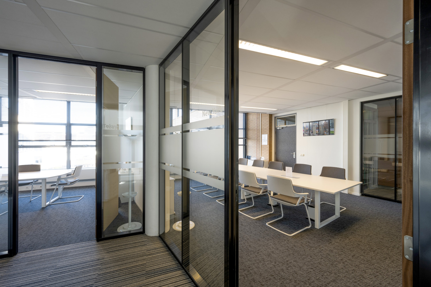 a glass walled meeting room with a table and chairs